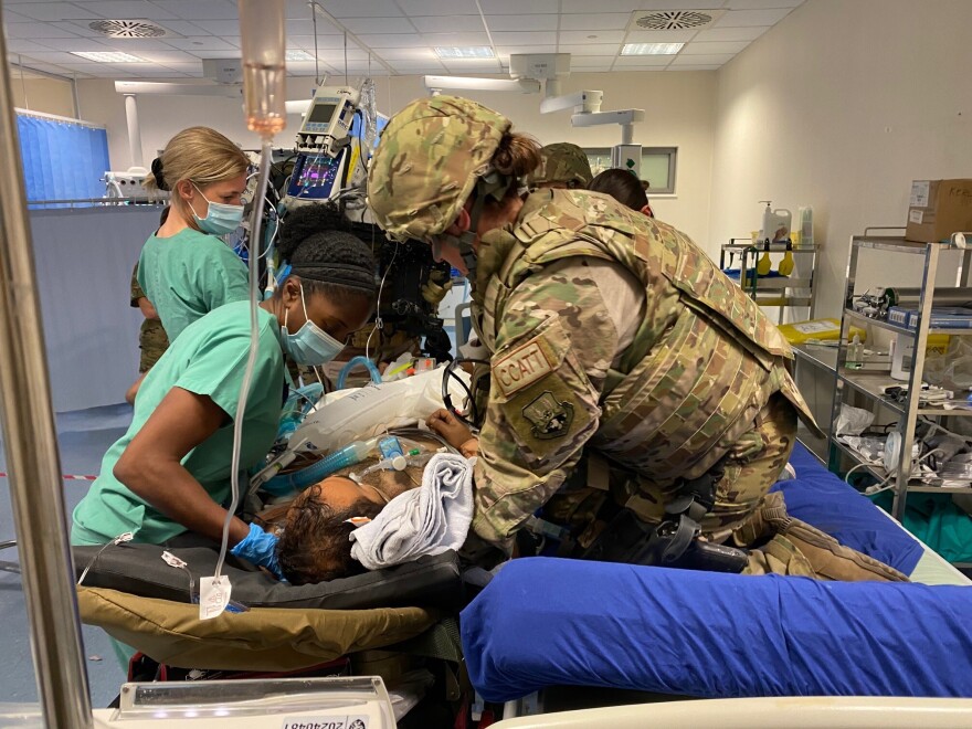 Critical Care Air Transport Nurse Maj. Katie Lunning helping a patient at the Coalition Hospital in Kabul, Afghanistan. Lunning and hospital staff are transferring the patient to their Critical Care Air Transport Team (CCATT) equipment to transport him to the next echelon of care. Lunning is wearing a helmet and Kevlar because she will be walking him through the streets back to the airplane.