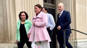 Four people are leaving a federal courthouse. They include two men and two women.